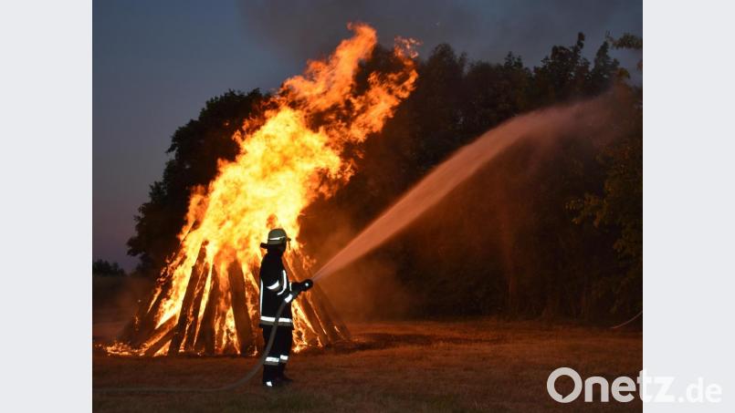 Feuerwehrmitglieder bewässern den Platz rund um das Johannisfeuer, so dass Gäste bedenkenlos feiern können. Bild: rgr