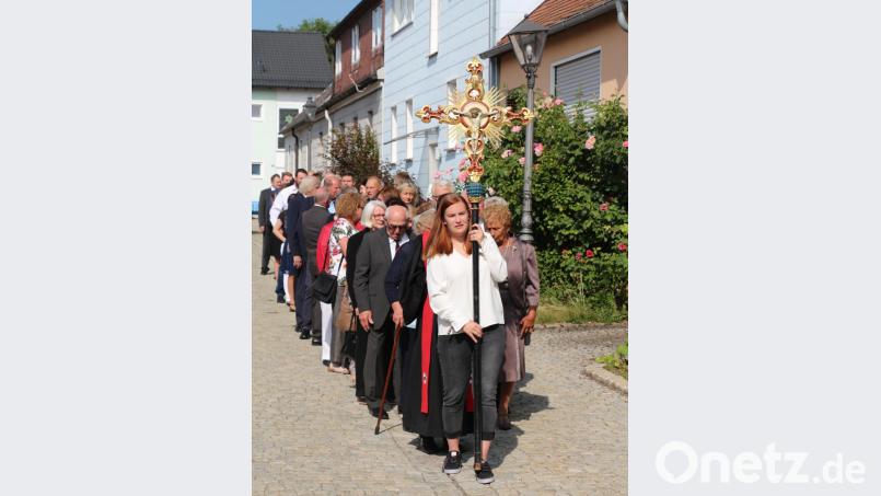 Dem Kreuz und Pfarrer Klausfelder folgend ziehen die Jubelkonfirmanden zur Dreieinigkeitskirche. Bild: rpp