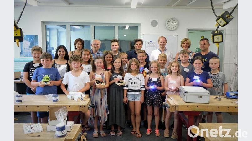 Stolz präsentieren die Kinder ihre gebastelten Werkstücke. Mit im Bild Betreuerin Ebru Küpür (Dritte von links), Susanne Freudenstein vom Verein TFK, Ausbilder Eduard Escherl, die Azubis Yannik Hägler und Stefan Sperl, Bürgermeister Konrad Kiener, Schulleiterin Diana Neidhard und Hausmeister Hans-Peter Geitner (hinten stehend von links) Bild: twi