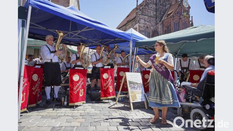 Besuch beim Nürnberger Hauptmarkt. Die „Weißbier-Resi“ Martina Bleistein greift zum Taktstock und dirigiert die Blaskapelle Ernestgrün. Bild: exb