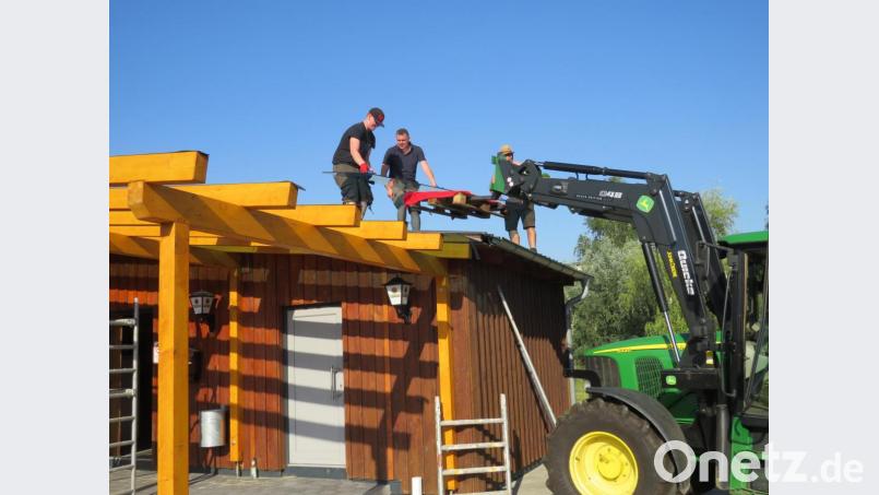 Mit einem Traktor wurden die Glasplatten nach oben gehoben und von den Helfern auf dem Holzvorbau ausgelegt und befestigt...... Bild: adj