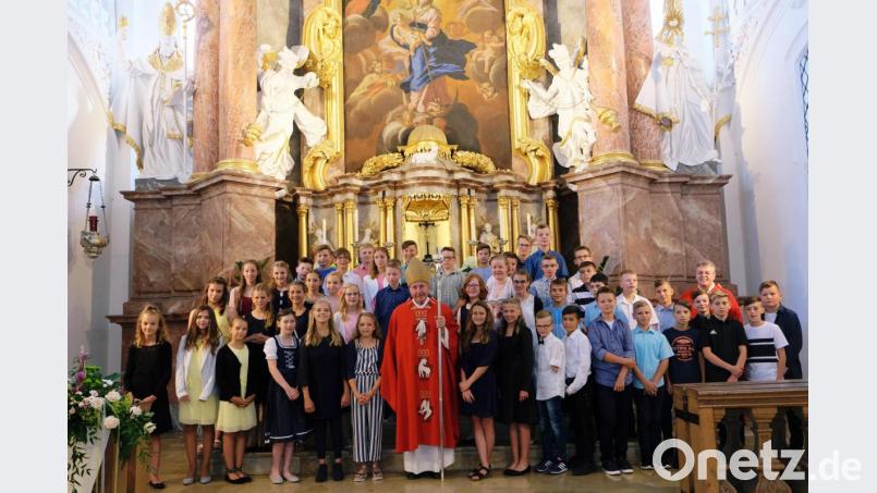 Der Firmspender, Generalabt em. Thomas Handgrätinger, und Pfarrer Adrian Kugler kommen gerne dem Wunsch nach einem Erinnerungsfoto mit den Firmlingen vor dem Hochaltar der Klosterkirche nach. Bild: do