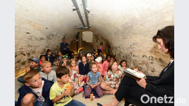Bürgermeisterin Tanja Schiffmann (rechts) liest Geistergeschichten, von Hexen und Gespenstern im tiefen Keller des Landrichterschlosses vor. Rektor Armin Aichinger (hinten links) hört wie die Kinder den spannenden Geschichten zu. Bild: bey