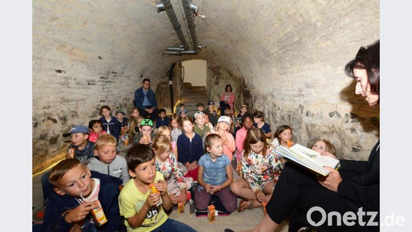 Bürgermeisterin Tanja Schiffmann (rechts) liest Geistergeschichten, von Hexen und Gespenstern im tiefen Keller des Landrichterschlosses vor. Rektor Armin Aichinger (hinten links) hört wie die Kinder den spannenden Geschichten zu. Bild: bey
