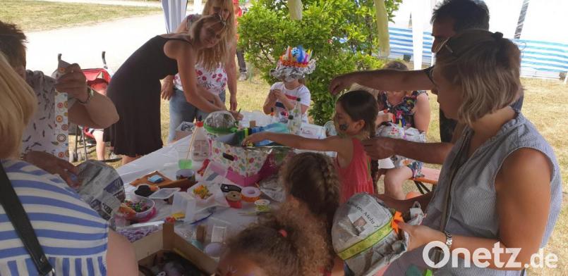 An dem heißen Samstagnachmittag sind die luftigen Sommerhüte am Infostand des Familienzentrums Mittendrin sehr gefragt. Bild: jzk