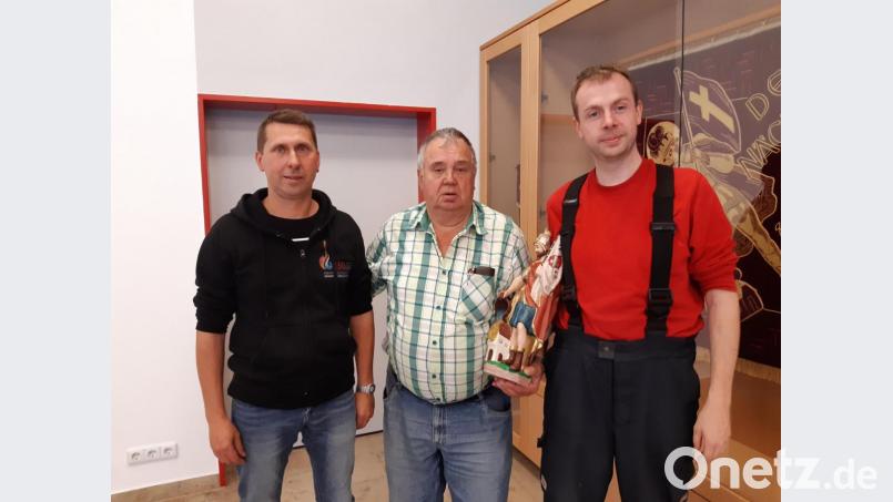 Karl-Heinz Flasch (Mitte) möchte seinen heiligen Florian in guten Händen wissen. Deshalb überreicht er die handgeschnitze Holzfigur der Feuerwehr. Vorsitzender Christian Münchmeier (rechts) und Robert Markt freuen sich darüber. Bild: Lowak