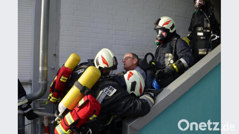 Die Feuerwehrleute tragen einen Mann, der im Rollstuhl sitzt, vom Balkon, auf den er sich geflüchtet hat, in Sicherheit. Bild: fz