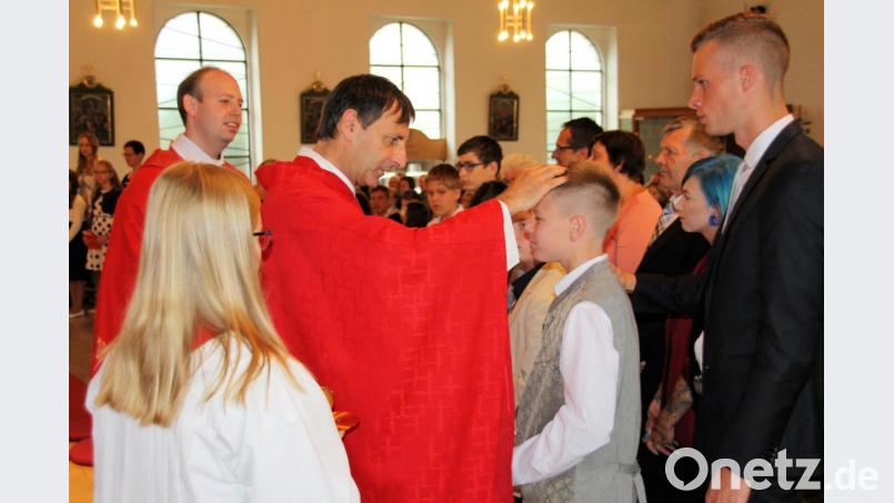 Domkapitular Thomas Pinzer legt in Schmidmühlen jedem Firmling die Hand auf den Kopf, zeichnet mit geweihtem Chrisamöl ein Kreuz auf seine Stirn, spricht ihn mit seinem Namen an und sagt „sei besiegelt durch die Gabe Gottes, den Heiligen Geist“. Bild: bjo