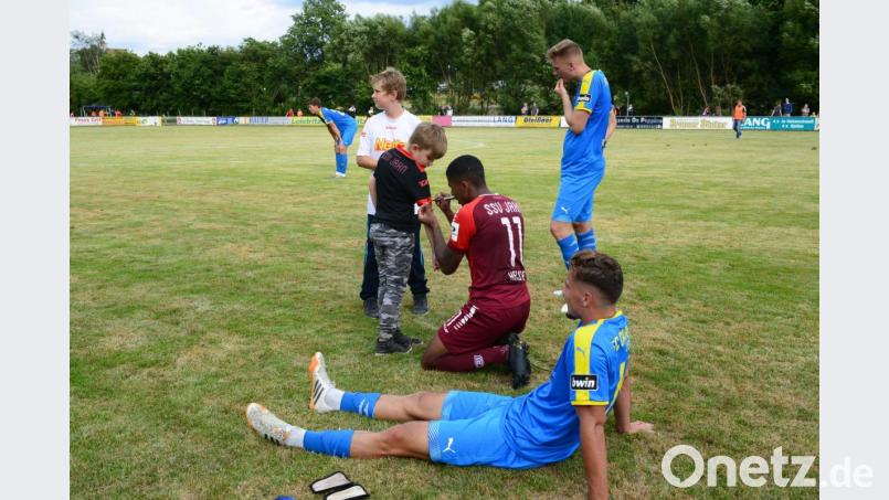 Einträchtig sitzen die Spieler beider Mannschaften nach dem Spiel auf dem Rasen und schreiben Autogramme auf Ärmel und Shirts. Bild: bey