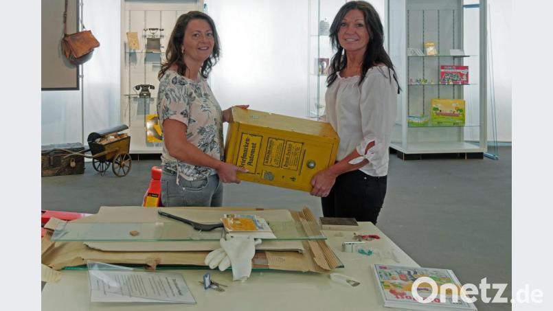 Nicole Schuller und Marion Papsch (von links) tragen beim Aufbau der Ausstellung einen Briefmarkenautomat aus dem Jahr 1936. Bild: tr