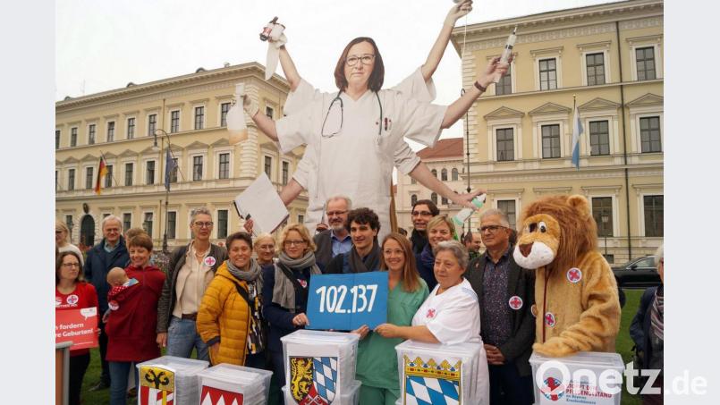 Natascha Kohnen (SPD) , Ates Gürpinar (Linke) und Pflegekräfte halten ein Schild mit der Zahl 102 137 Bild: Stefan Jagel