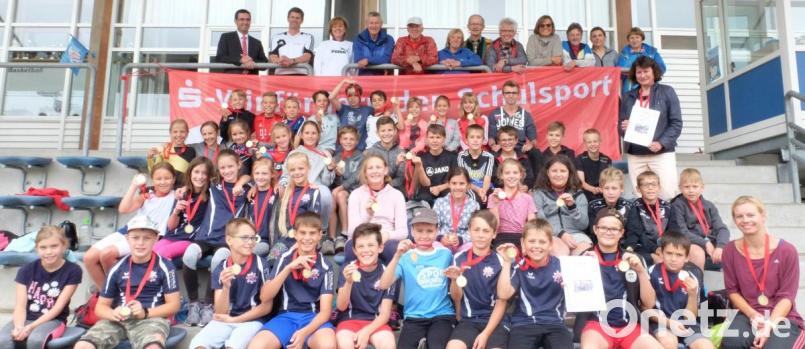 Punktgleich belegten beim Grundschulwettbewerb Leichtathletik 2019 die ersten Plätze Schwarzenfeld (vorne mit Betreuerin Maria Birzer) und Nabburg (Waltraud Gietl, stehend rechts). Mit im Bild Gebietsdirektor Gerhard Süß von der Sparkasse (links), die Fachberaterinnen beim Staatlichen Schulamt Schwandorf Renate Raab (Dritte von links) und Eva Wagner (Zweite von rechts) sowie das Kampfrichterteam. Bild: ohr