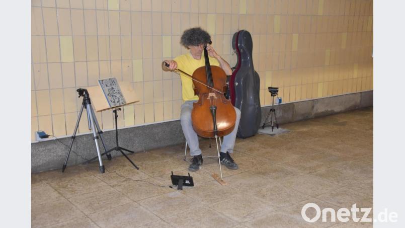 Marcus Kaiser ist nicht nur Maler und Bildhauer, sondern auch Musiker und Komponist. Ganz versunken spielt er während der Öffnungszeiten seiner Ausstellung in der Bahnhofsunterführung in Regensburg auf seinem Cello. Bild: mip