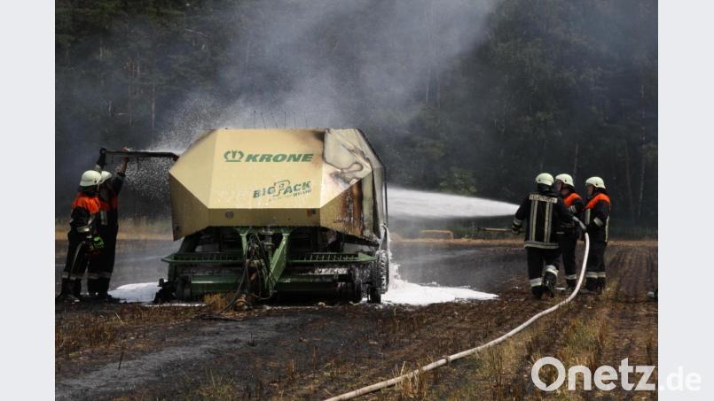Feuerwehrleute löschen eine Heuballenpresse und das Stoppelfeld bei Neudorf. Bild: Zaruba