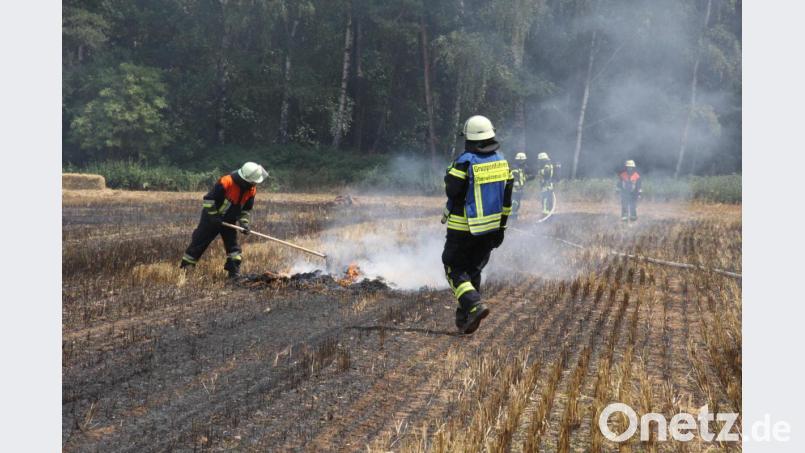 Feuerwehrleute löschen eine Heuballenpresse und das Stoppelfeld bei Neudorf. Bild: Zaruba