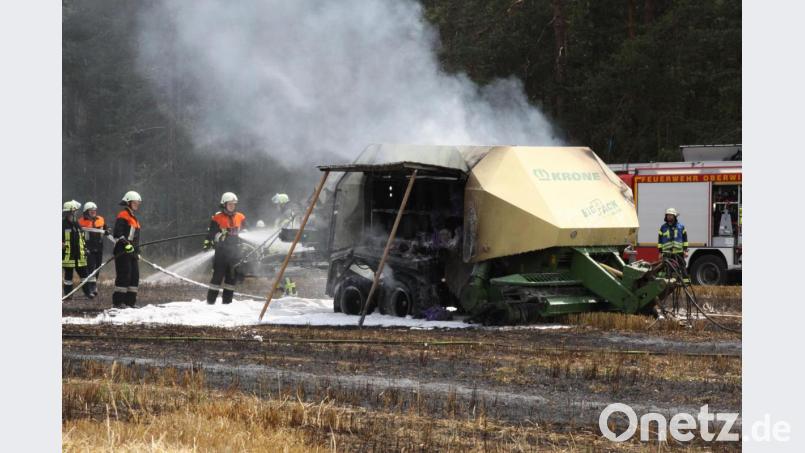 Feuerwehrleute löschen eine Heuballenpresse und das Stoppelfeld bei Neudorf. Bild: Zaruba