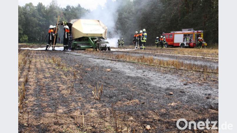 Feuerwehrleute löschen eine Heuballenpresse und das Stoppelfeld bei Neudorf. Bild: Zaruba