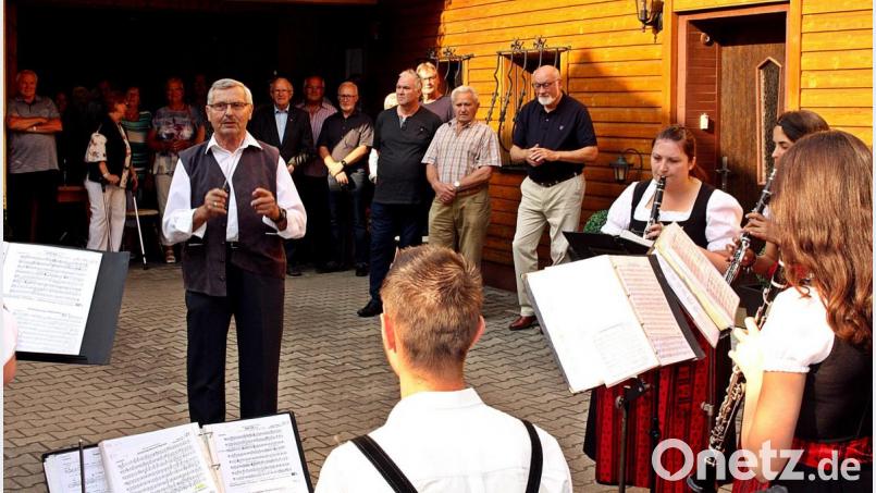 Das Geburtstagskind Josef Kammerer beim Dirigieren der Blaskapelle. Seine Gratulanten im Hintergrund schauten und hörten zu, ob die Takte auch richtig eingesetzt wurden. Bild: zer