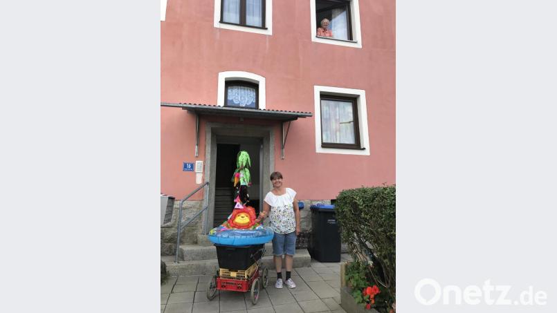 Der größere der beiden Wägen ist dem Sommer entsprechend als Badeinsel dekoriert; vom Fenster aus beobachtet Irmgard Bauer das Fotoshooting ihres Lichtblicks. Bild: eig