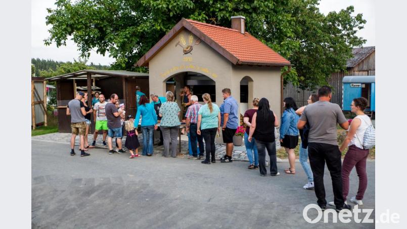 Lange Schlangen bilden sich vor dem steinernen Holzbackofen, in dem Zwiebelkuchen und Pizza zubereitet wurden. Bild: sml