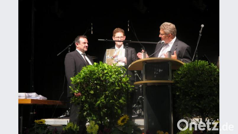 Realschuldirektor German Helgert und Fachoberlehrer Mathias Frischholz verabschieden Stadtpfarrer Konrad Amschl (von rechts) mit einem originellen Geschenk. Bild: jzk
