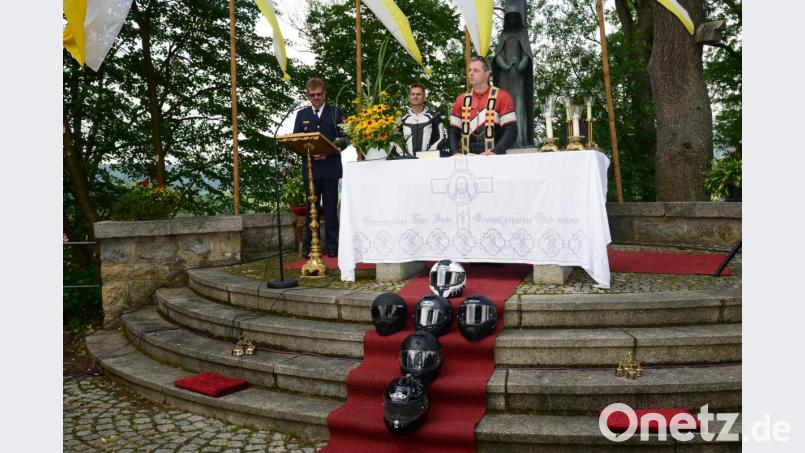 Die Motorradhelme sind am Freialtar zum Kreuz gelegt. Pater Thomas Mühlberger in Motorradkleidung und Stola bittet die Biker den Gruß bei der Begegnung auf der Straße als gegensetigen Segen zu verstehen. Bild: bey