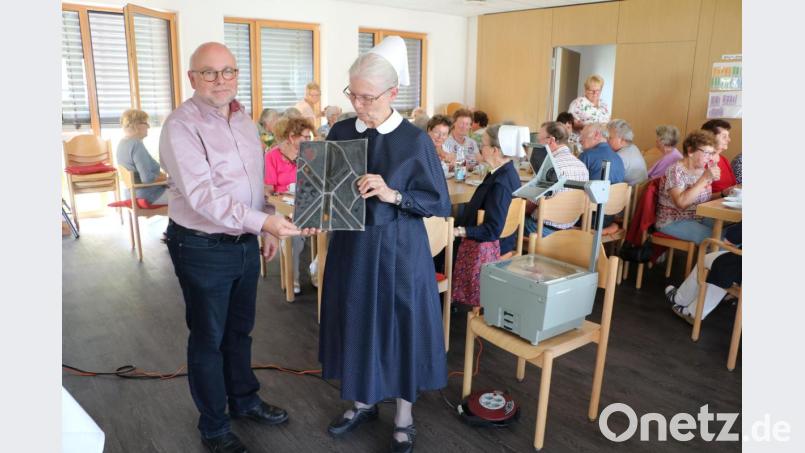 Pfarrer Matthias Ahnert bekommt von Schwester Brigitte Fortmüller ein Glasbild aus dem früheren Bestand des Pfarrhauses. Bild: gru