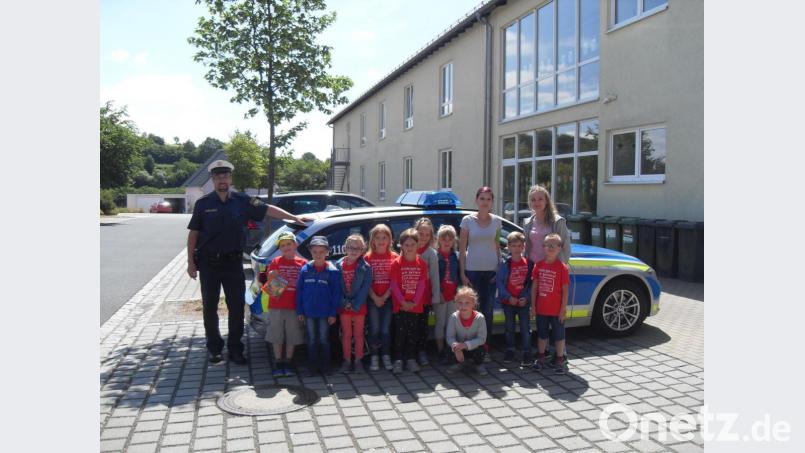 Polizist Carsten Landgraf zeigt den Vorschulkindern und den Erzieherinnen Anja Kirchberger und Silke Kiefer (von links) sein Polizeiauto und dessen Ausstattung. Bild: rpp