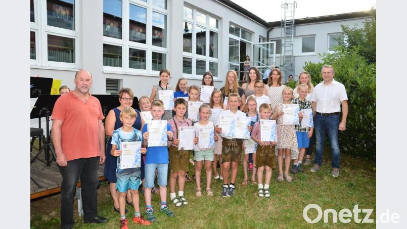 Musikalischer Leiter Hermann Mack (links) und zweiter Vorsitzender Josef Schmucker (rechts) verleihen an 26 Musikschüler Urkunden und Abzeichen für die bestandenen Qualifizierungen. Bild: fjo