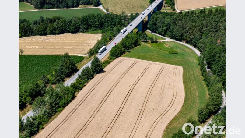 Autos fahren auf der Bundesstraße 16 zwischen Feldern und Wald (Luftaufnahme mit einer Drohne). Ein 46-Jähriger Jäger soll bei einer Gruppenjagd in dem Feld im August 2018 einen Schuss abgegeben haben, der einen Mann durch die Seitenscheibe eines vorbeifahrenden Autos an der Straße tödlich traf. Knapp ein Jahr nach einem mutmaßlichen Jagdunfall muss sich der Jäger vor dem Landgericht Amberg verantworten. Bild: Armin Weigel/dpa