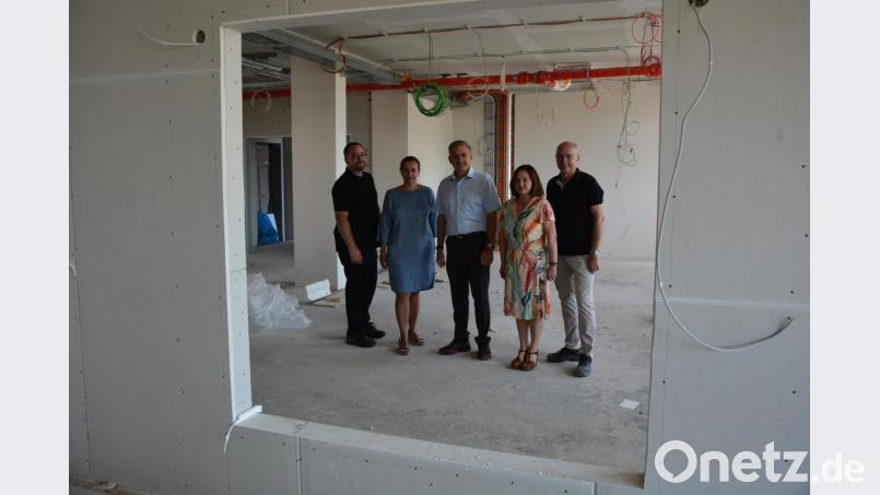 Bauleiter Mirko Bertl, Konrektorin Gabriele Stock, Bürgermeister Roland Grillmeier, Schulleiterin Renate Zuber und Architekt Armin Juretzka (von links) schauen beim Rundgang durch eine Fensteraussparung, durch die künftig ein Blickkontakt zwischen den Klassenzimmern möglich ist. Bild: jr