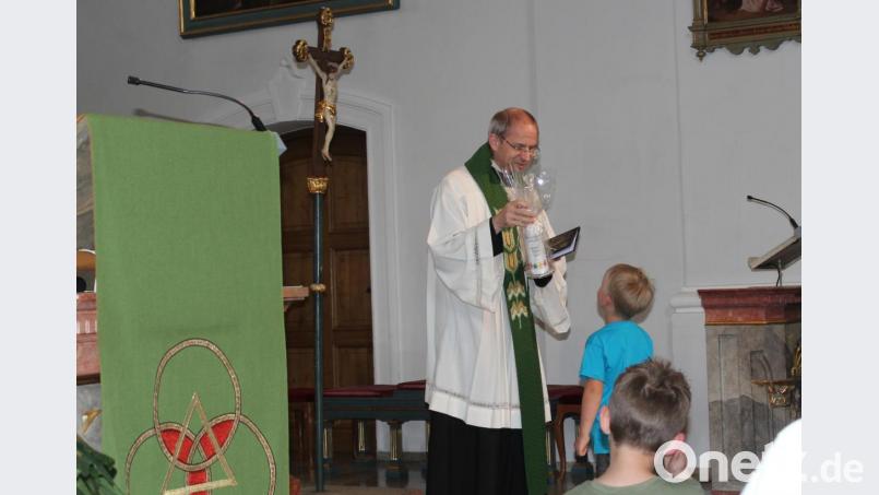 Im Namen des Kinderhauses überreicht eines der Kinder Pfarrer Hofmann zu dessen Abschied eine Kerze. Bild: Susanne Forster