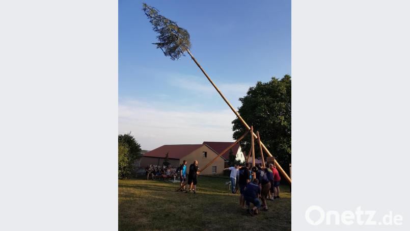 Mitglieder der Feuerwehr Thurndorf und der KLJB richten unter Anleitung von Kommandant Manuel Müllner das Kirwasymbol auf. Im Hintergrund spielt die Thurndorfer Blasmusik. Bild: hzi
