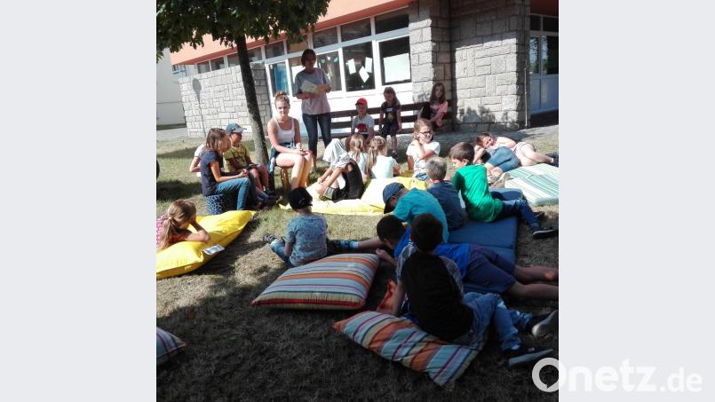 Die Zweitklässler machen es sich auf den Polstern und Sitzkissen vor der Marktbücherei gemütlich. Bild: exb