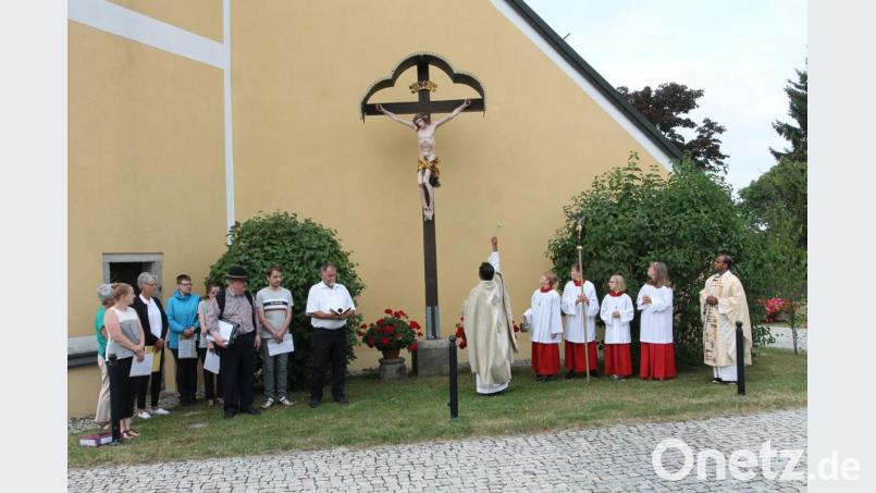 Pfarrer Julius Johnrose segnet das von Kirchenpfleger Josef Meckl und Kunstmaler Reinhold Schultes restaurierte Missionskreuz. Bild: pi