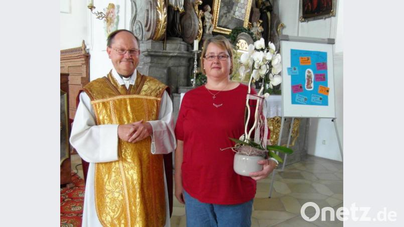 Pfarrer Heribert Stretz überreicht zum Abschied eine Orchidee an Madlen Heser. Bild: hl