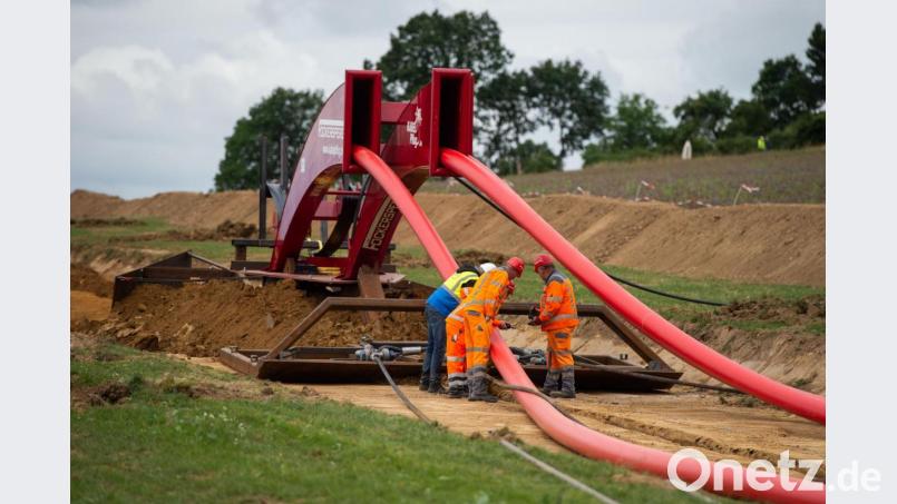 Bauarbeiter stehen in Niedersachsen auf einer Baustelle vor einem Mehrfachpflug zur Verlegung von Drehstromerdkabeln. Bild: Christophe Gateau/dpa