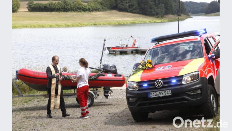 Pfarrer Stefan Wagner segnete den neuen Transporter der Marke &quot;Amarok&quot; (rechts) und das Schlauchboot (links) &quot;Hubert&quot; (links). Bild: Hirsch