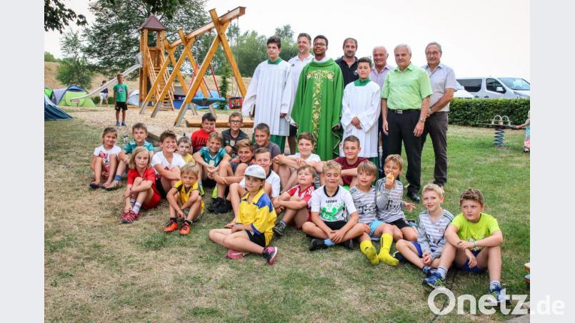 Mario Kotlar, Wolfgang Groß, Heribert Griener, Josef Gößner (hinten von links), Pfarrvikar Justin Kishimbe, Bürgermeister Günter Kopp (stehend, Dritter und Siebter von links) freuen sich mit den Kindern über den erneuerten Spielplatz. Bild: Gemeinde Kulmain/exb