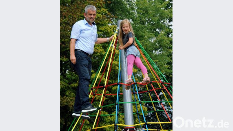 Zusammen mit der sechsjährigen Anna erklimmt Bürgermeister Roger Hoffmann die Seil-Pyramide auf dem neuen Traßlberger Kinderspielplatz. Bild: gfr