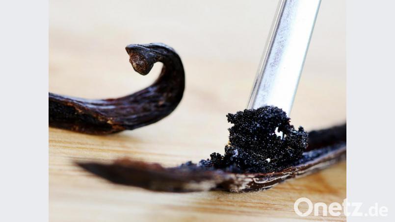 Das Mark einer Vanilleschote wird mit einem Löffelstiel herausgeschoben. Bild: Roland Weihrauch/dpa