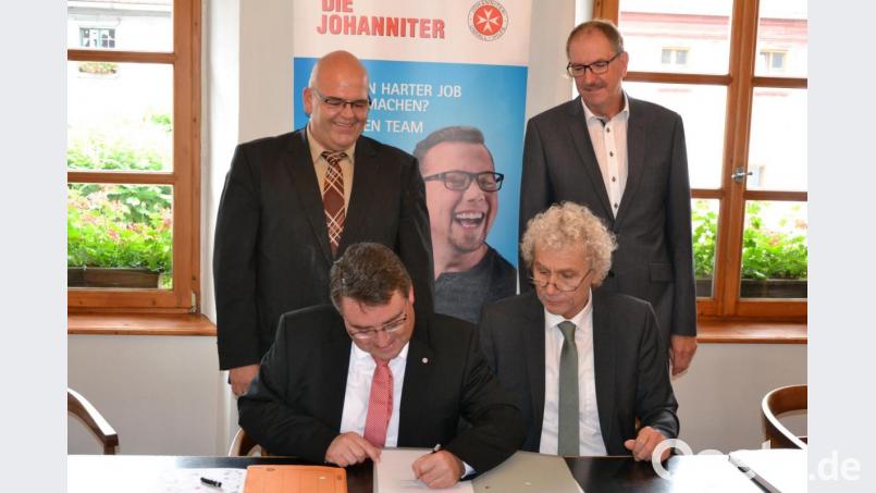 Martin Steinkirchner, Regionalvorstand Ostbayern der Johanniter-Unfall-Hilfe, und Landrat und stellvertretender ZRF-Verbandsvorsitzender Wolfgang Lippert (von links) unterzeichneten den Betreibervertrag zum neuen Rettungswagen-Standort in Wernersreuth. Bürgermeister Klaus Meyer und Alfred Rast, ZRF-Geschäftsleiter, schauen den beiden über die Schulter. Bild: rti