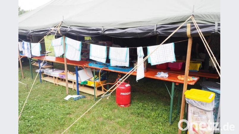 Im Küchenzelt lagern Messer, Kochlöffel und Töpfe. Hinter der Wäscheleine mit den Geschirrtüchern warten die zwei Gaskocher auf ihren Einsatz, um 75 hungrige Mäuler zu versorgen. Bild: bl