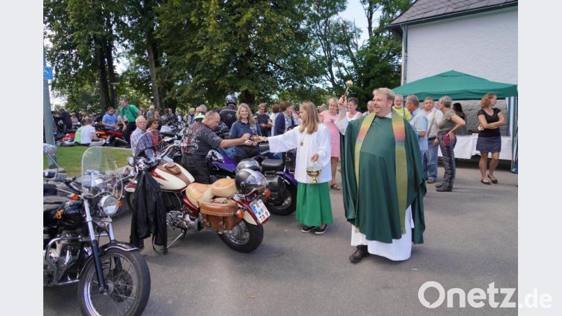 Pfarrer Albert Hölzl bei der Segnung der Motorräder, dabei werden kleine Fisch-Schlüsselanhänger an die Biker verteilt. Bild: fvo