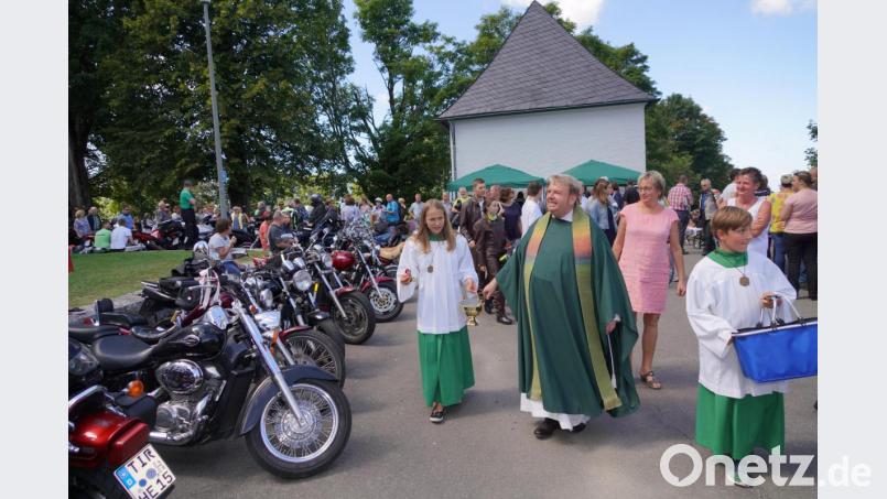 Pfarrer Albert Hölzl bei der Segnung der Motorräder, dabei werden kleine Fisch-Schlüsselanhänger an die Biker verteilt Bild: fvo