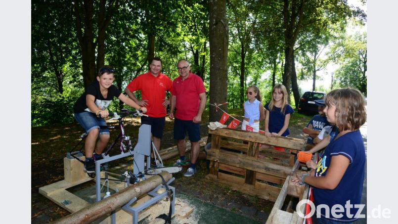 Per Pedal und Kettensäge eine Scheibe vom Baum abschneiden: Die Konstruktion von Christoph Witt (im roten Shirt links) macht es möglich. Bild: bey