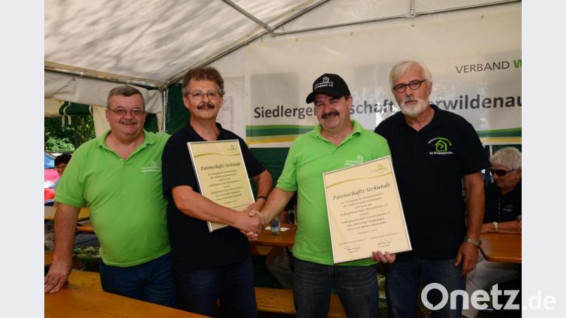 Die Vorsitzenden der Siedlergemeinschaften Schwarzenfeld und Oberwildenau, Hans-Peter Hierl und Helmut Grünbauer, besiegeln die Patenschaft per Handschlag und Austausch der Patenschaftsurkunden. Zweiter Vorsitzender Artur Leonhardt (links) und Rudi Boritzka (rechts) freuen sich ebenfalls. Bild: bey