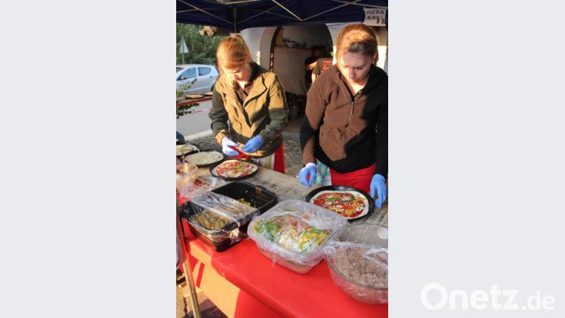 Fleißige Frauen belegen die Pizzen mit leckeren Zutaten. Bild: kro