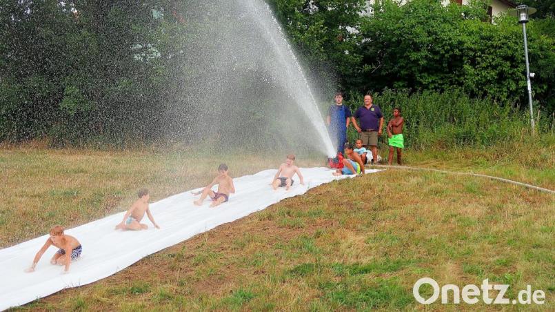 Die künstliche Wasserrutsche, gespeist aus einem angrenzenden Bach, wurde zum Renner beim Ferienprogramm der Feuerwehr. Bild: bsc