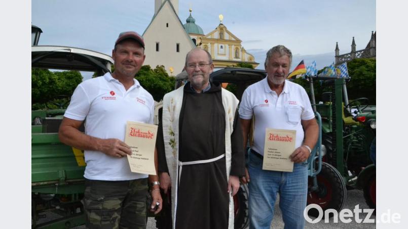 Seit Anfang an dabei: Für ihre zehnte Anreise mit dem Bulldog nach Altötting sind Paul Ippisch (links) und Organisator Johann Fischer (rechts) mit einer Urkunde geehrt worden. Pater Andreas Kaiser hatte die Wallfahrer aus der Oberpfalz begrüßt. Bild: exb